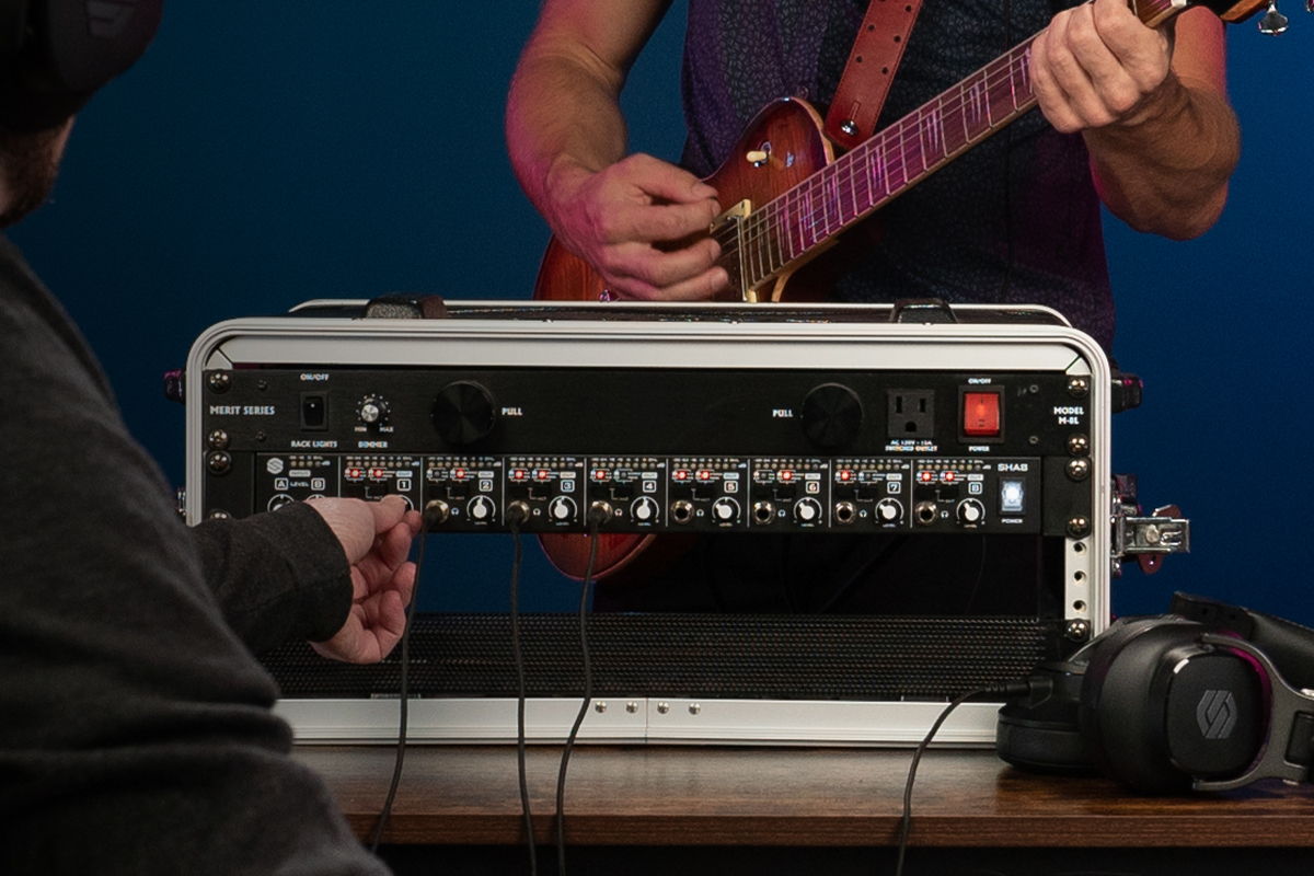 Sterling SHA8 8-channel rackmount headphone amplifier being setup in a studio with guitar player close up.